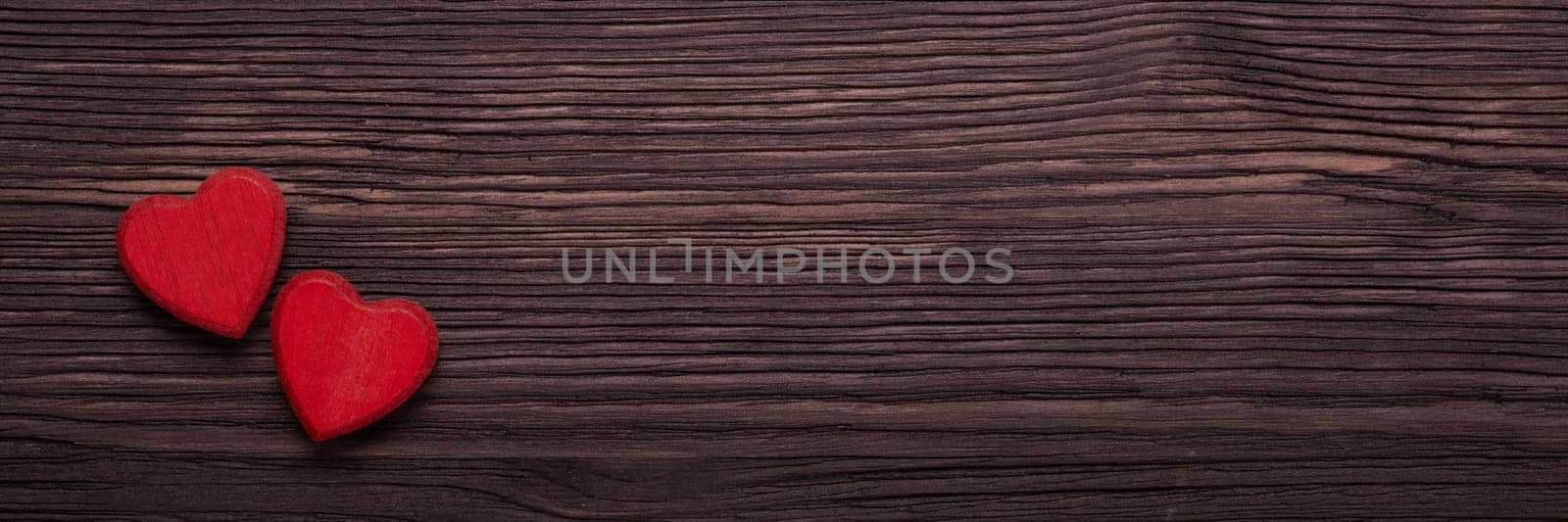 Two decorative hearts on dark brown wooden background. Top view with copy space. Valentine's Day. Design element for romantic greeting card, wedding invitation. Extra wide panorama banner background