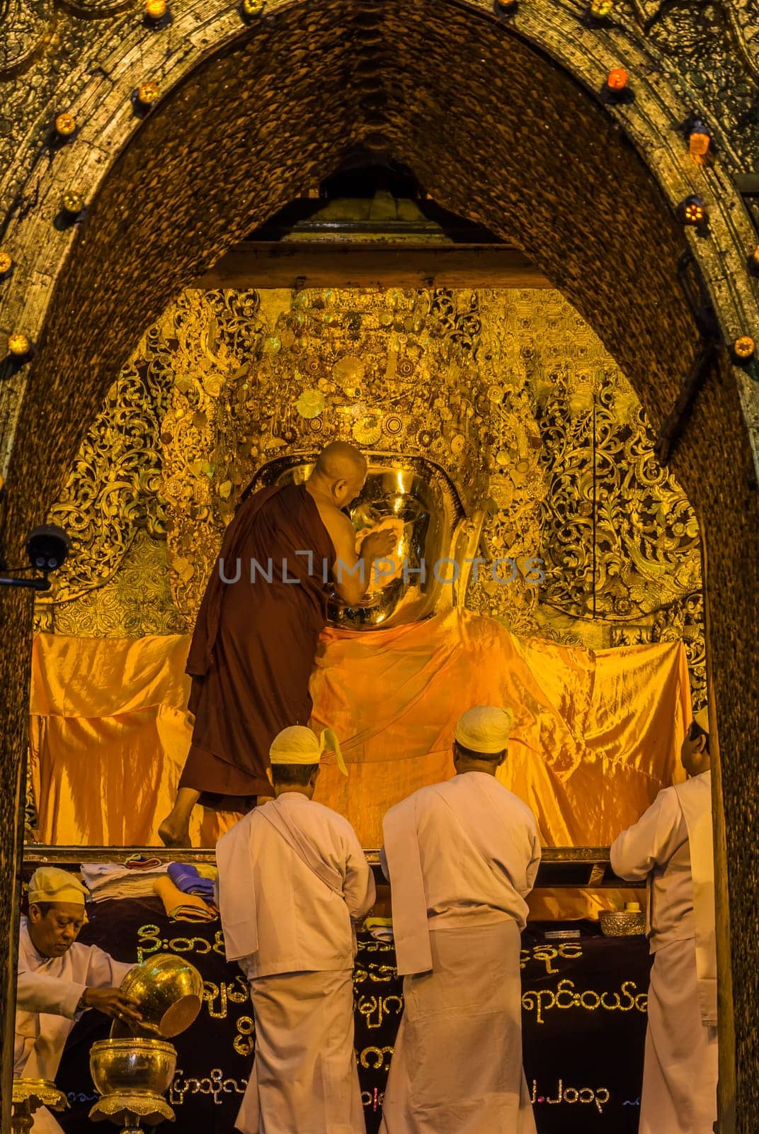 Early morning senior monk cleaning the face of Mahamuni Buddha in Mandalay, Myanmar