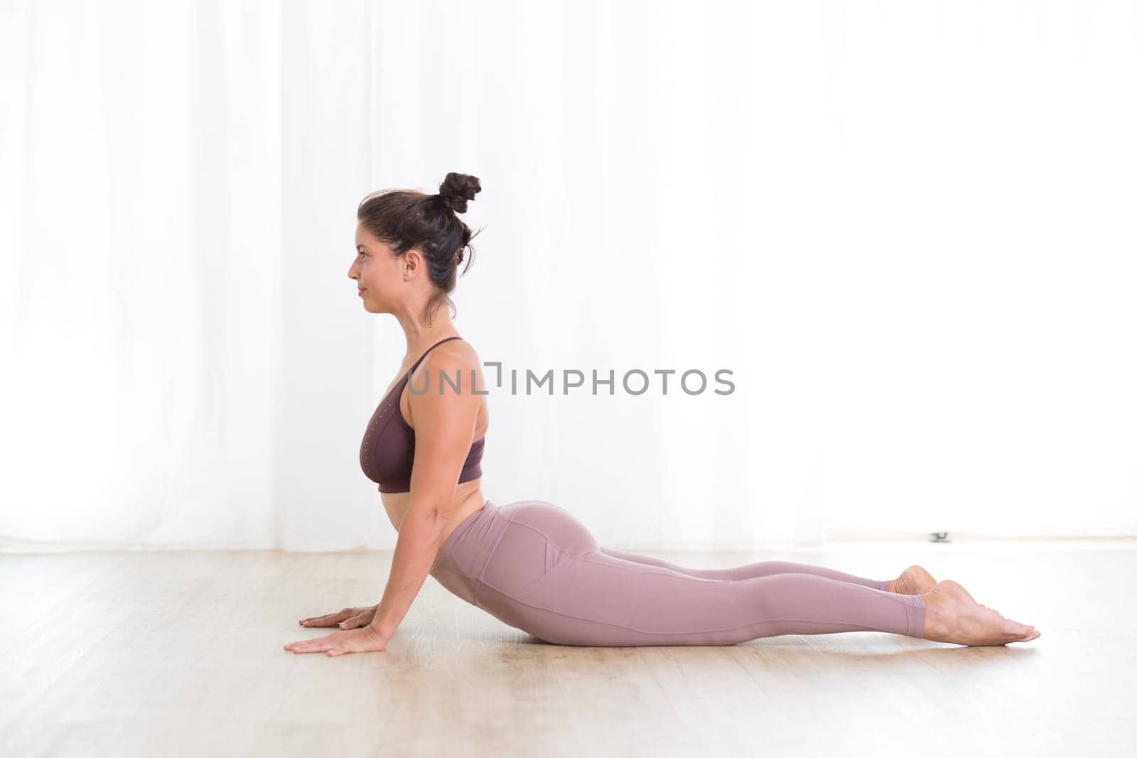 Portrait of gorgeous active sporty young woman practicing yoga in studio. Beautiful girl practice Sasangasana, rabbit yoga pose. Healthy active lifestyle, working out indoors in gym.