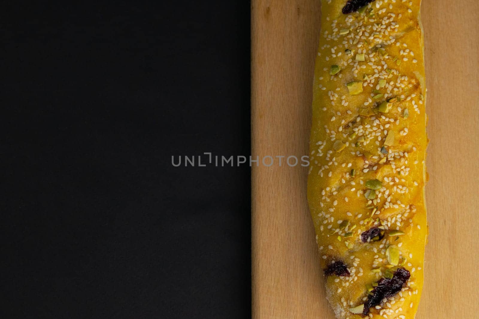 Freshly prepared puff pastry with cherry and sesame seeds close-up in a black background. Details The concept of home baking, breakfast, snack.