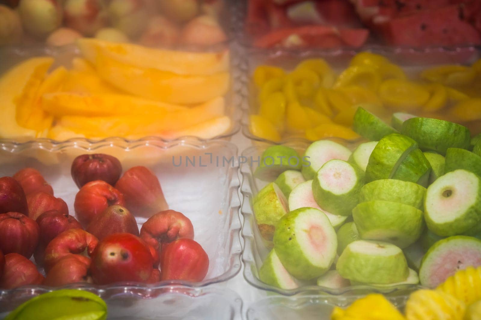 Glass bowls with freshly cut delicious juicy fruits for sale on market in China