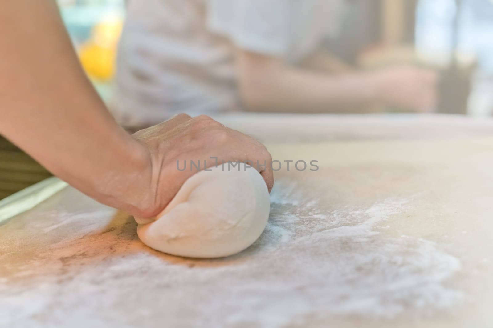 Person hand rolling out the dough made from flour, which will be used for the making of traditional chinese dumplings during cooking class in a travelers hostel, Chengdu, China