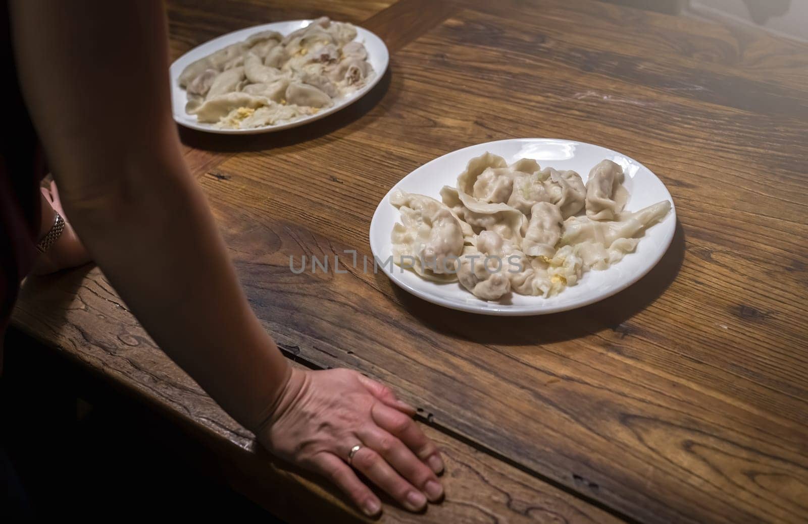 Student resting on her hands and looking at plates of ready freshly cooked dumplings made during chinese dumpling making and cooking class in a travelers hostel, Chengdu, Sichuan Province, China