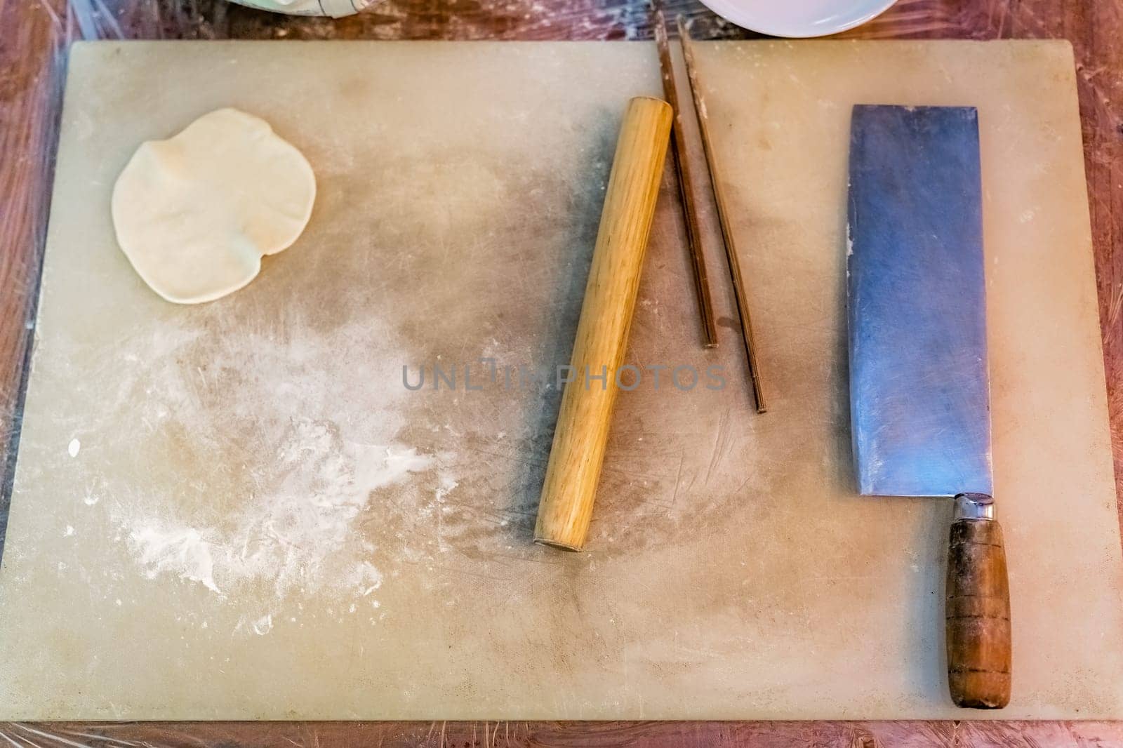 Chopping board, knife, rolling pin and chopsticks which will be used for the making of traditional chinese dumplings during cooking class in a travellers hostel