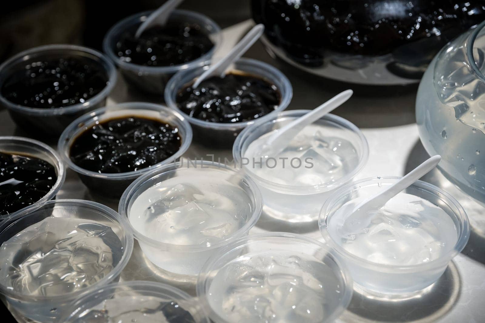 Plastic transparent bowls with sweet jelly chinese dessert on a self service breakfast buffet table in a restaurant