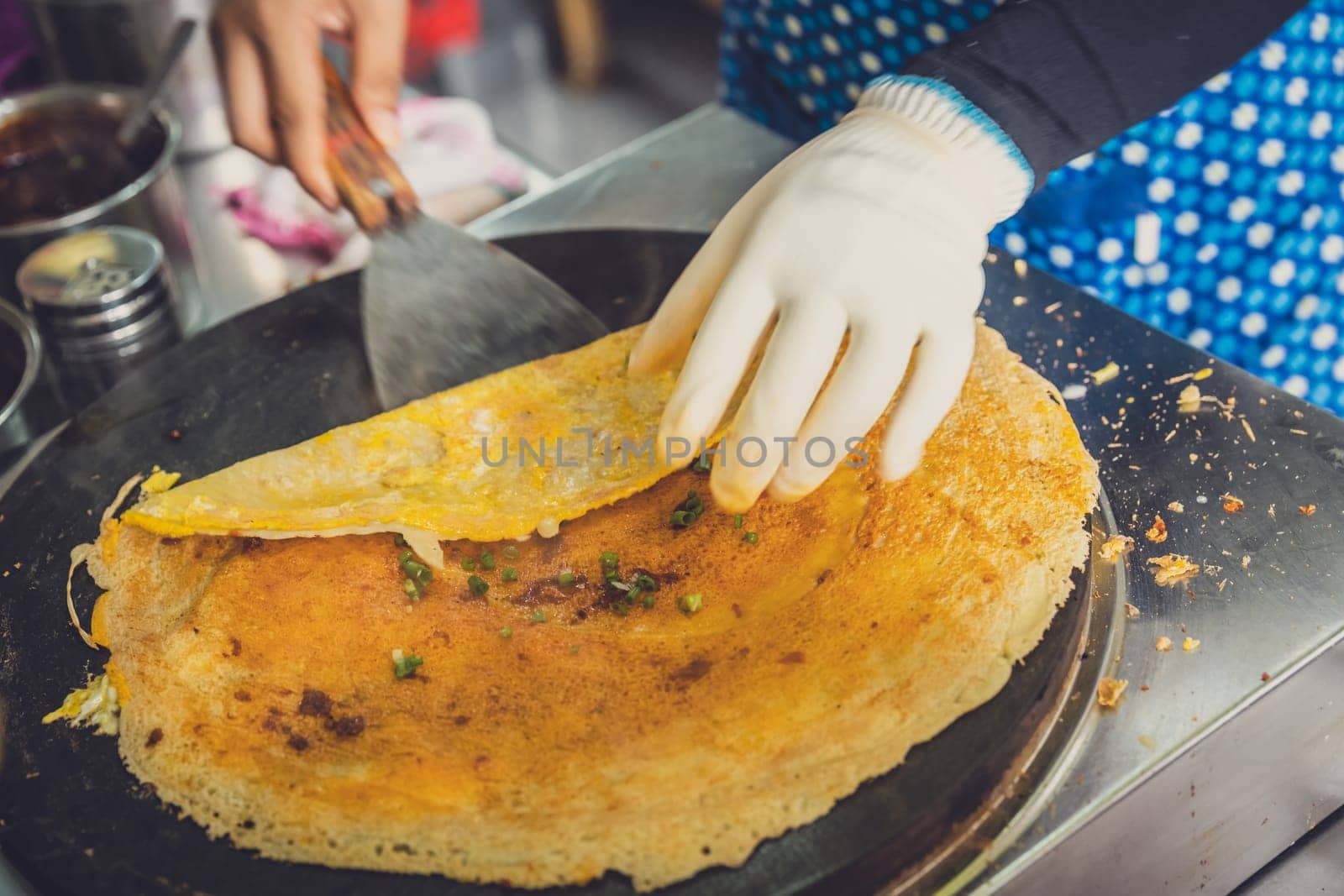 Woman folding and making savoury egg pancake in a small local street outlet bakery in Yichang town, China
