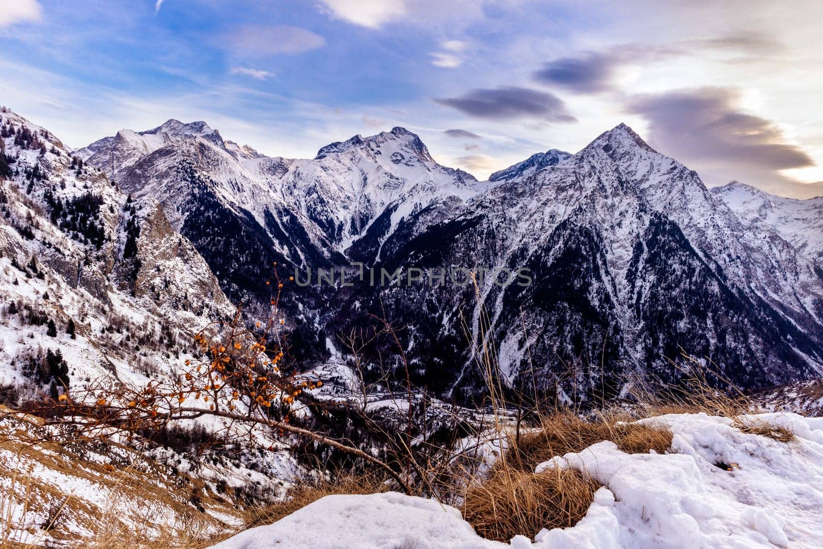 View from outskirts of Les deux Alpes village on mountain range with long yellow grass. Sunset at French alps, Auvergne Rhone region, France