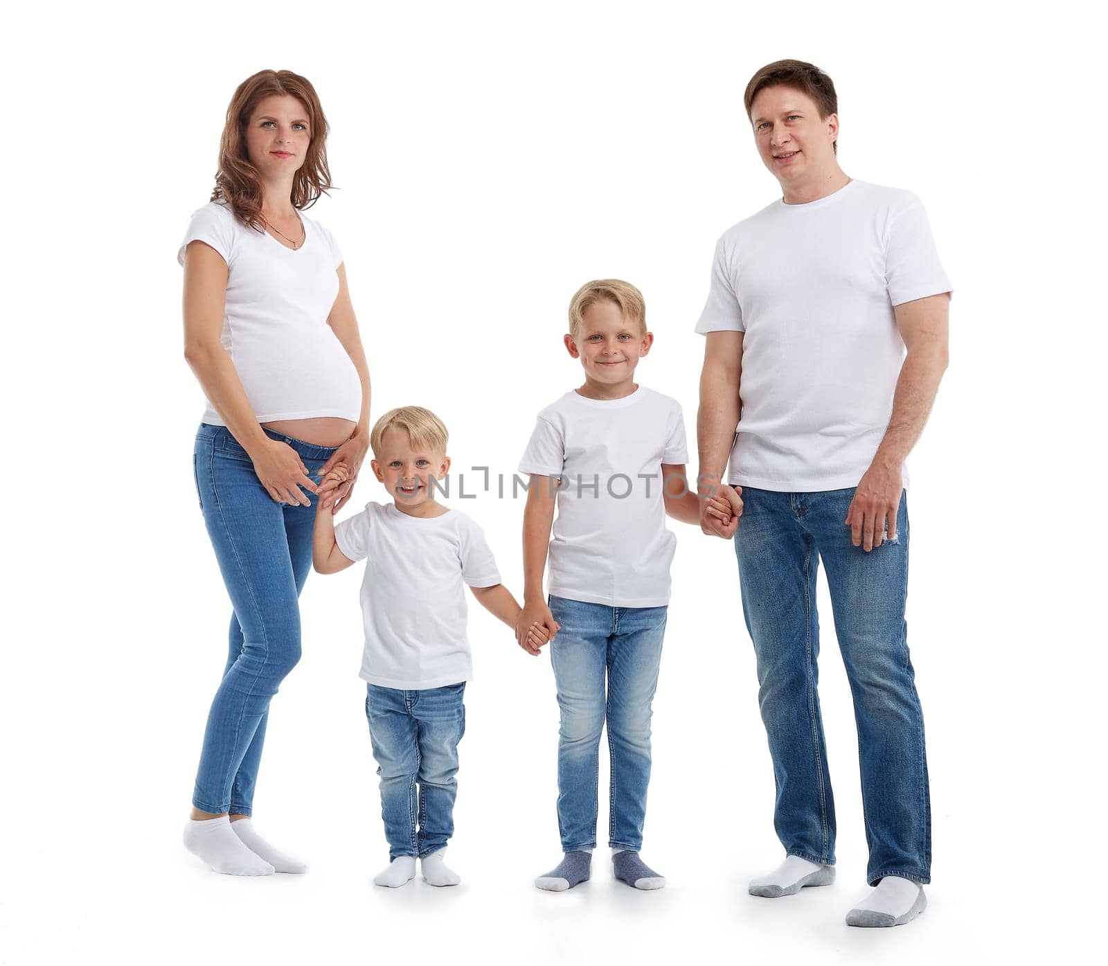 Happy parents: pregnant mother and father with lovely two sons are stand holding hands and smiling, isolated on a white background. Happy friendly family. Concept of people and family