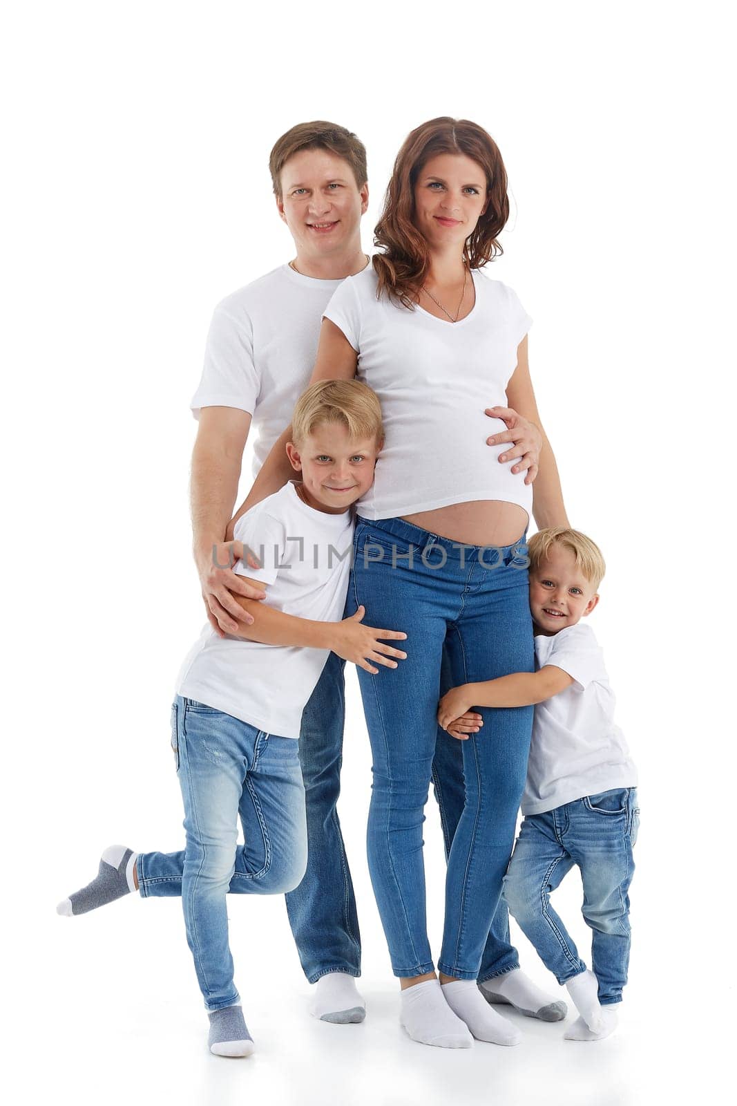 Friendly family. Husband with two sons are smiling and embracing pregnant woman, isolated on a white background.  Happy parents. Pregnant mother and father with children. Concept of people and family