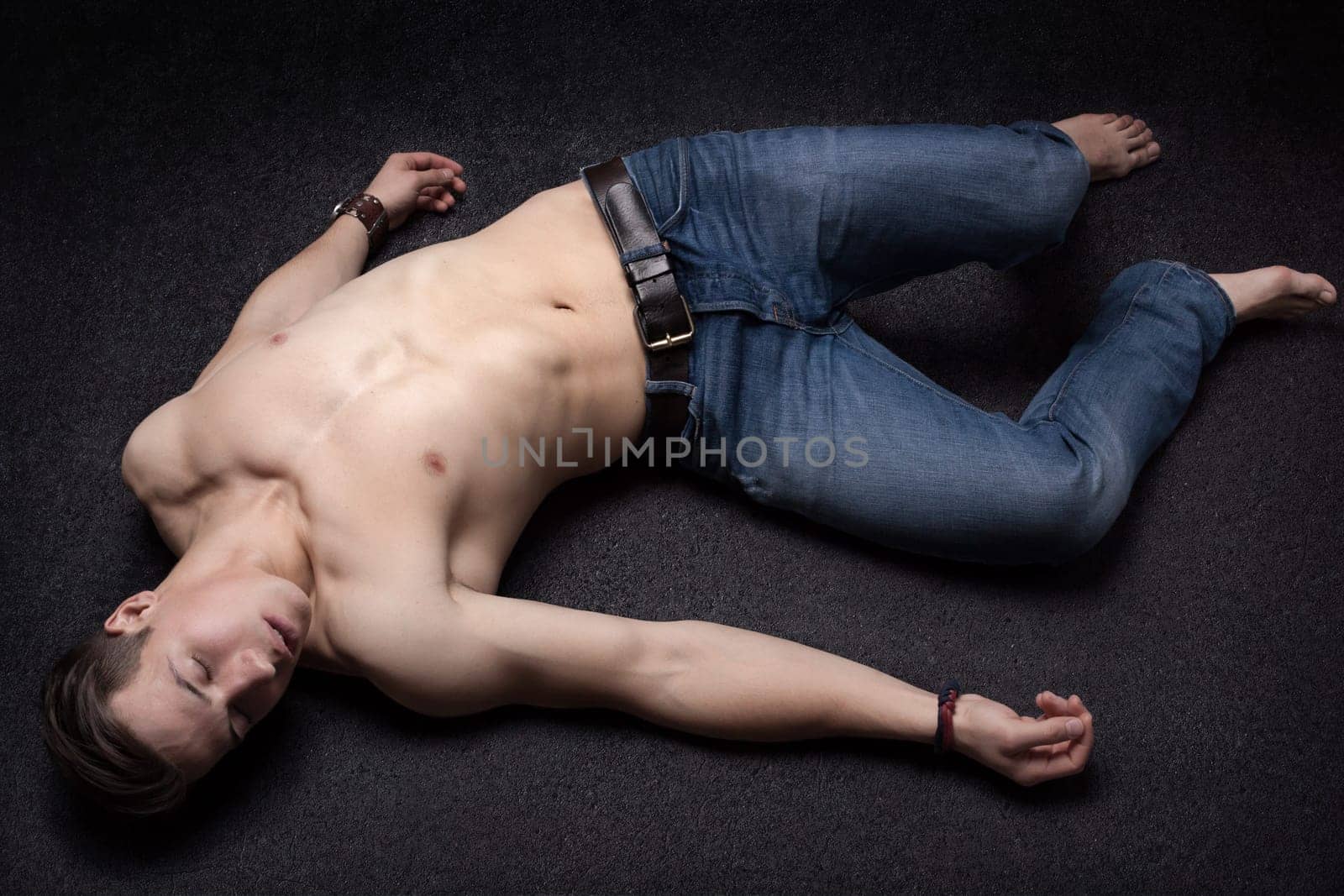 Young sportsman lying down unconsciously on apparent asphalt floor