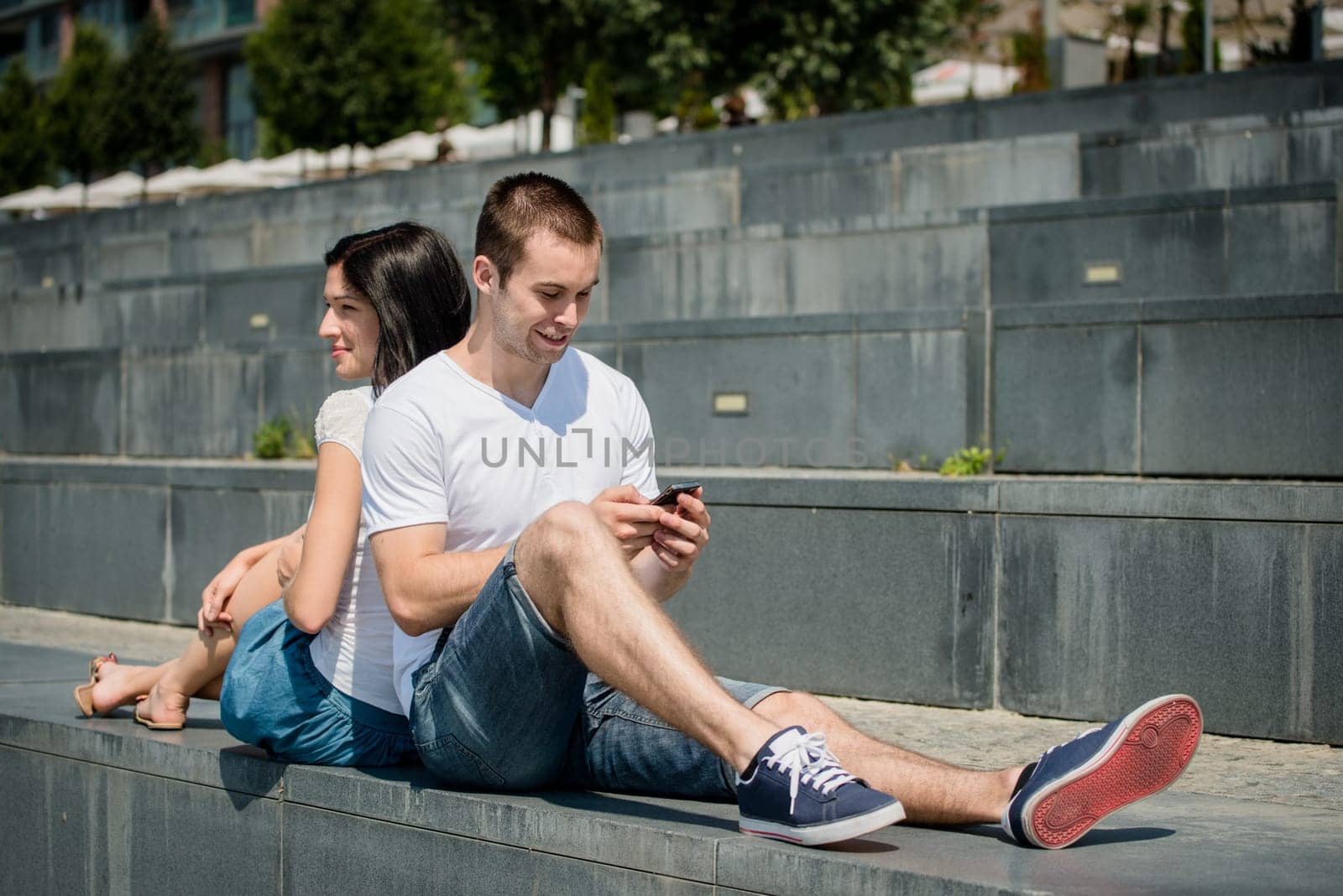 Young couple relaxing outdoor in street - man with smartphone