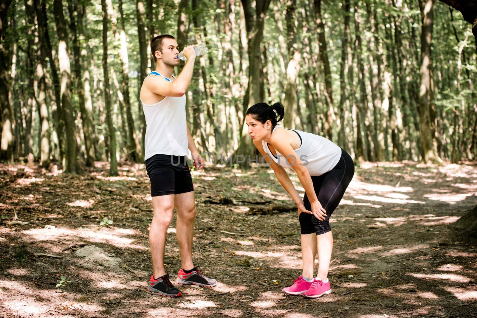 Sporting together - young couple relaxing after jogging in nature