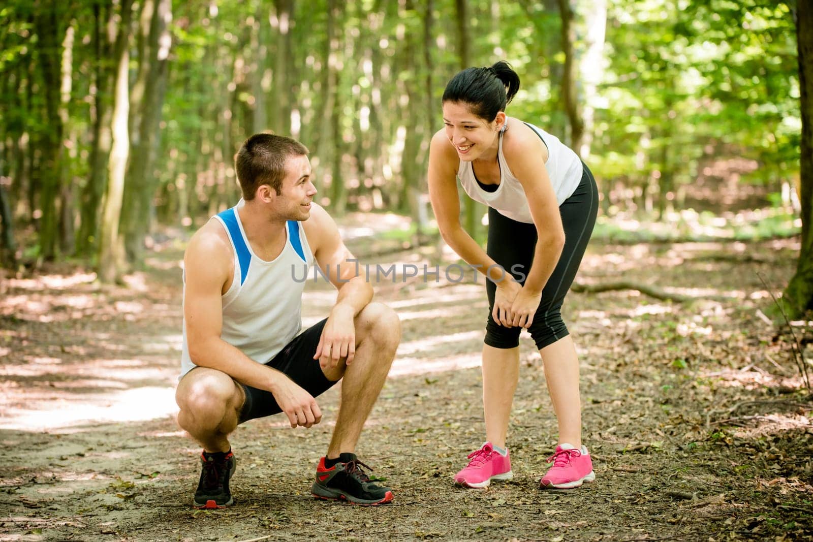 Sport couple relaxing after jogging in nature (foot bridge in forest)