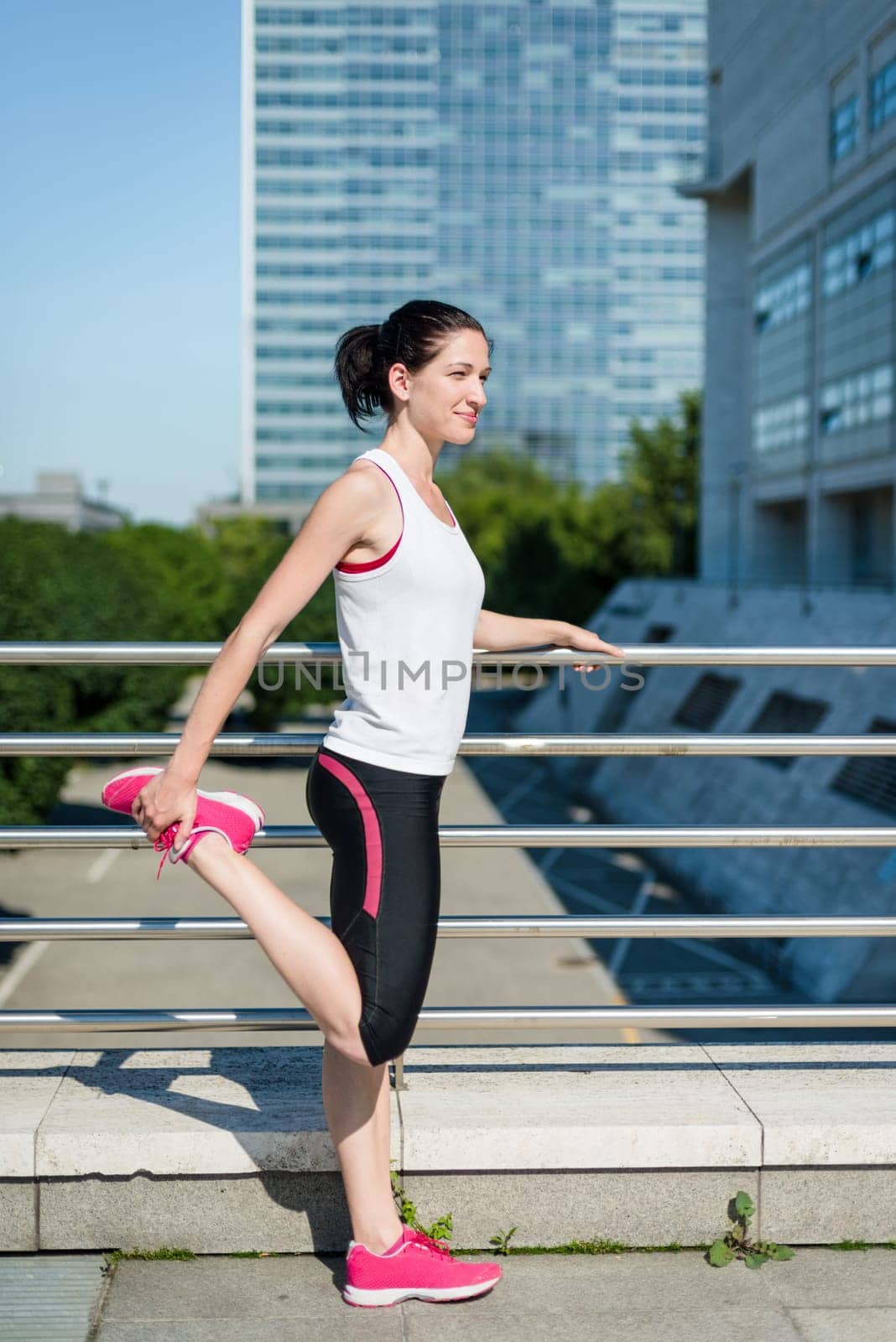 Young sport woman is stretching leg before jogging - outdoor in city