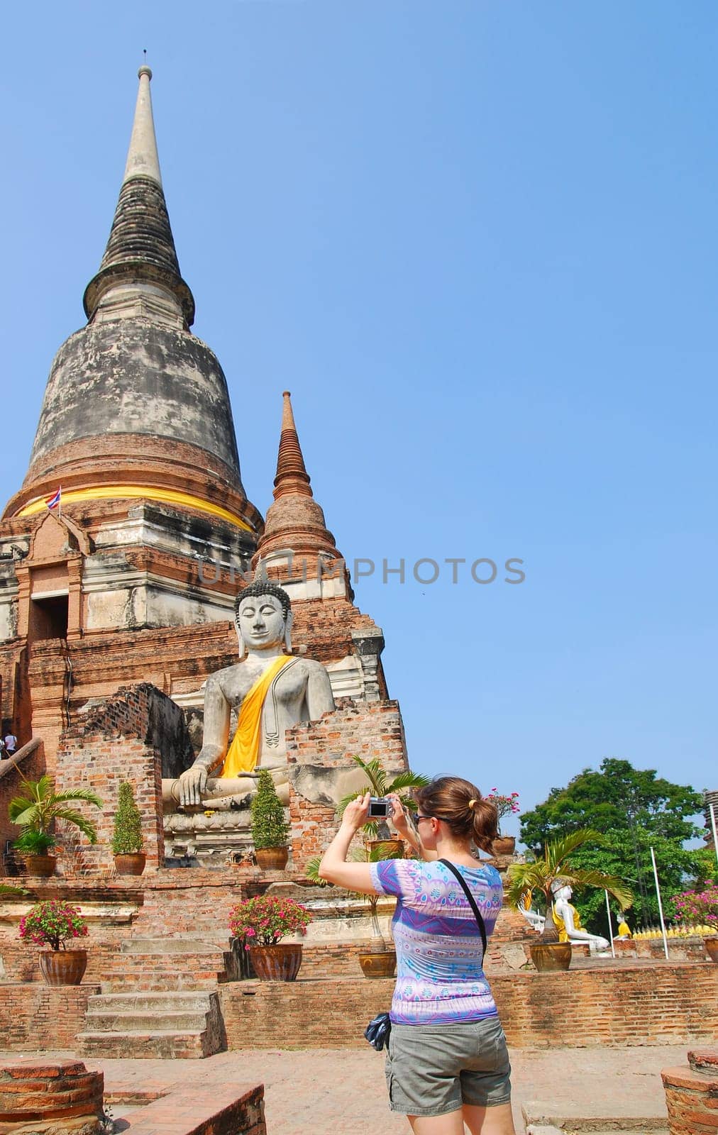 Tourist (young woman) taking picture of budhist stupa in Ayutthaya, Thailand