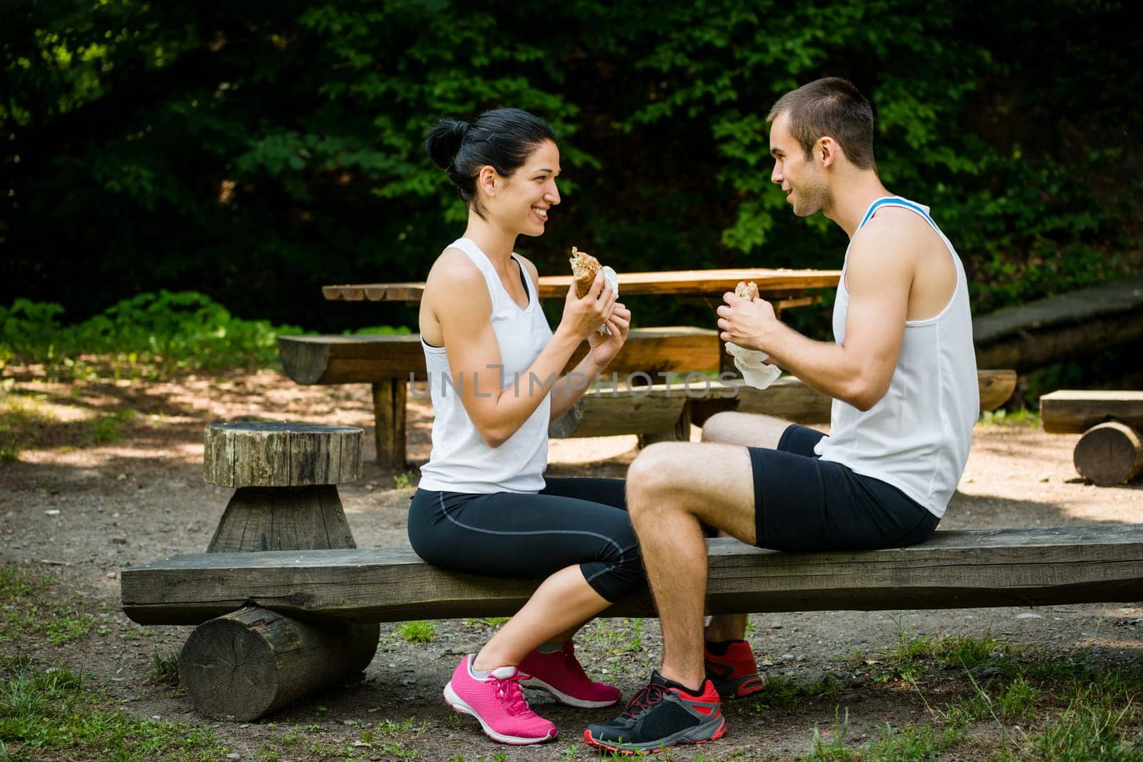 Young couple eating together after jogging outdoor in nature