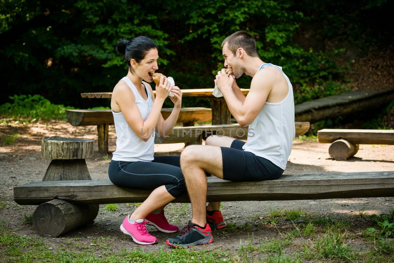 Young couple eating together after jogging outdoor in nature