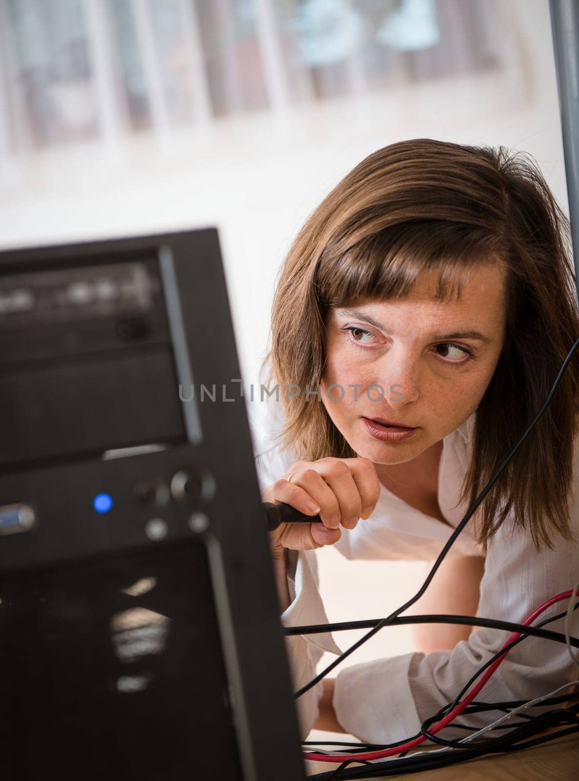 Young business woman trying to repair computer under table