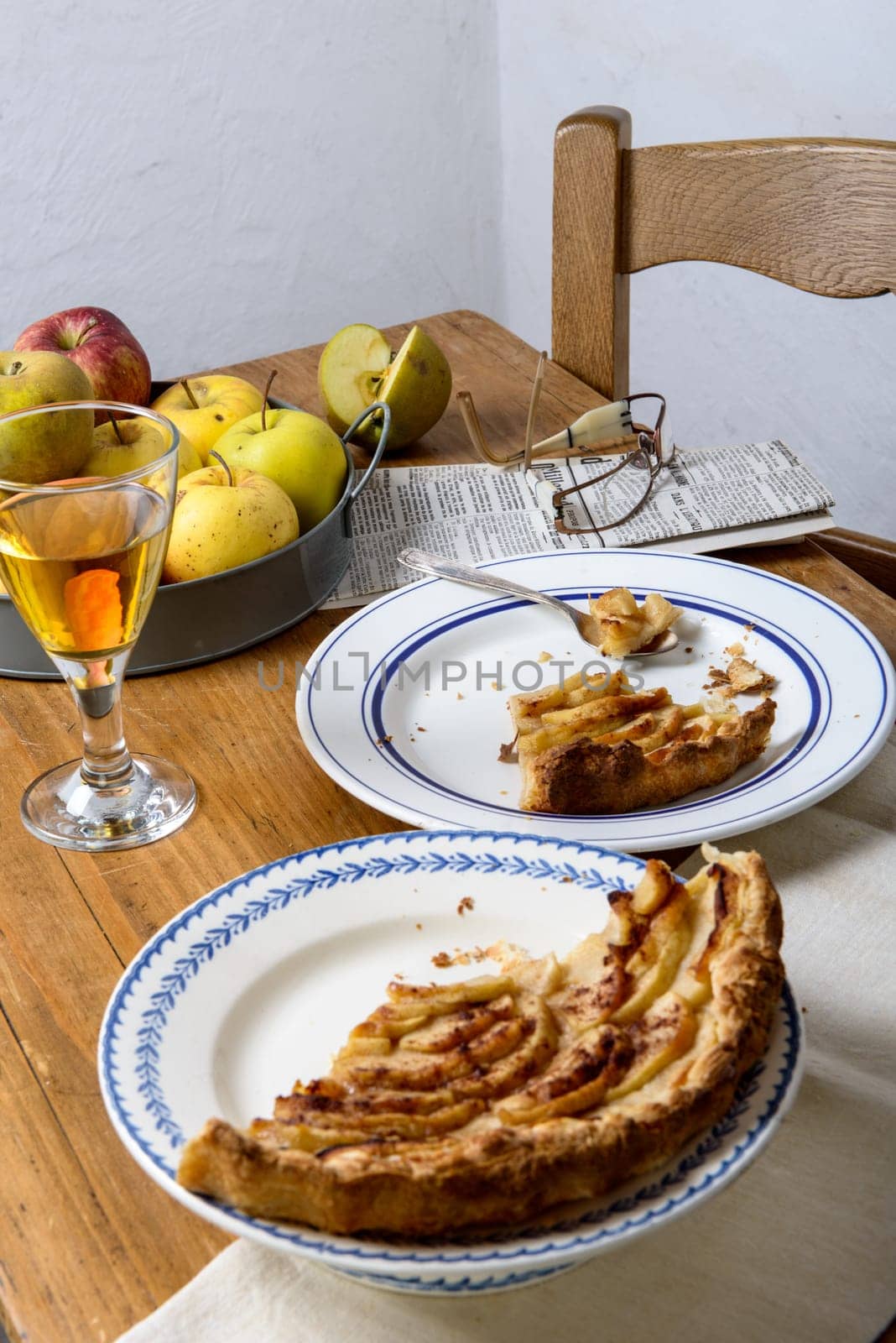 apple pie on a table with apples and glass of cider