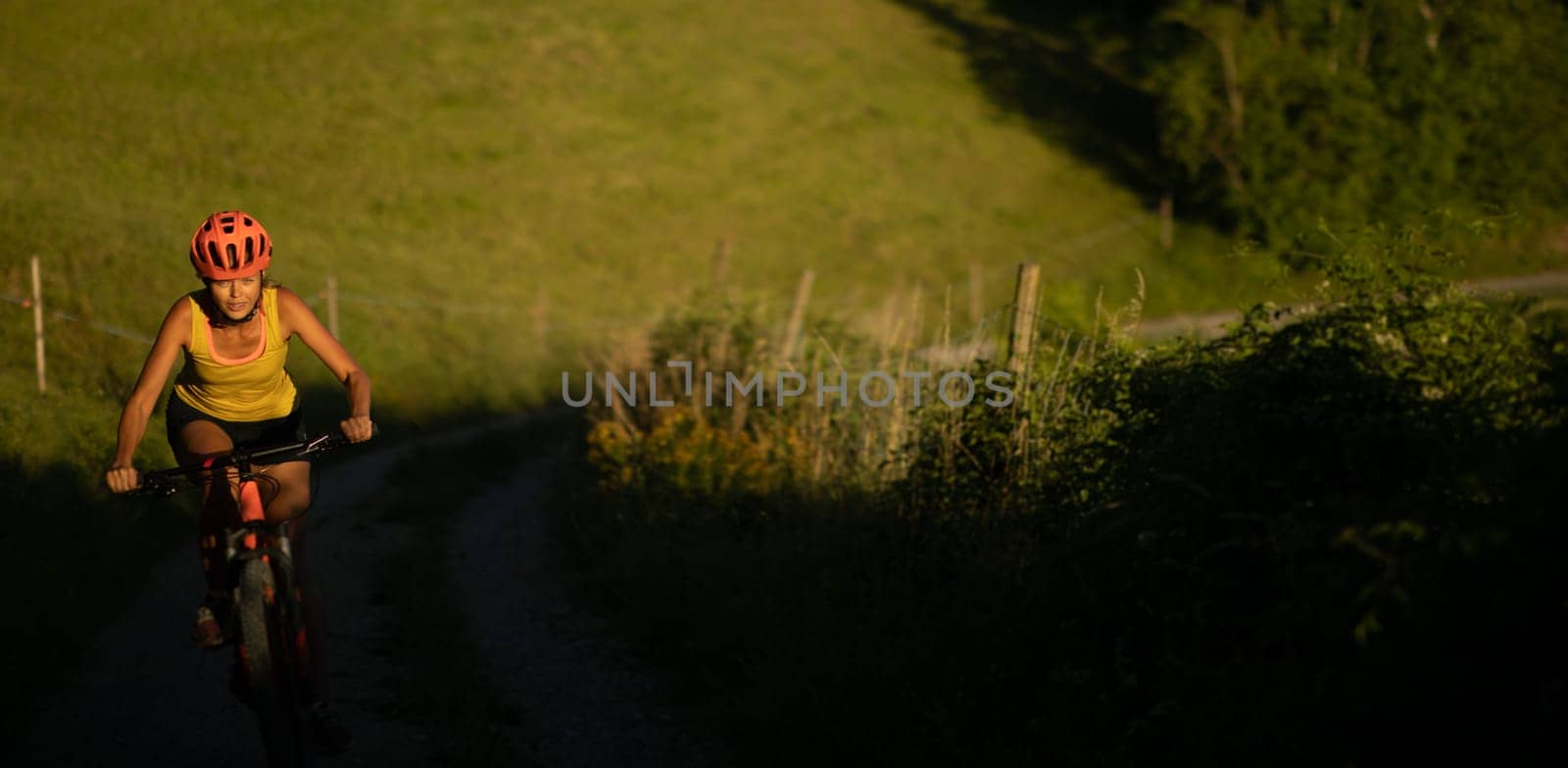 Pretty, young woman biking on a mountain bike enjoying healthy active lifestyle outdoors in summer (shallow DOF)