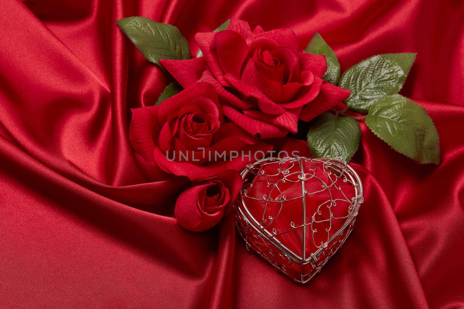 Abstract background from red silk (satin), roses and heart. Fabric texture with draped. Top view. Element design. Valentine's day. Wedding day.  Women' s day. Greeting card