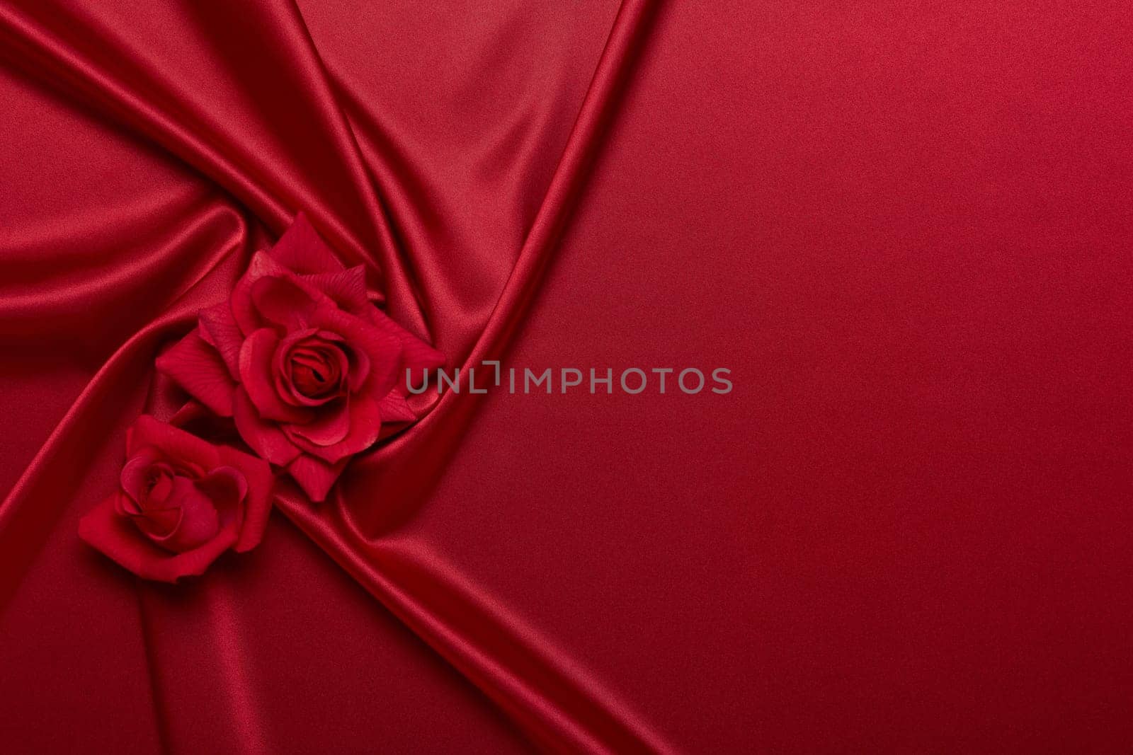 Abstract background from red silk (satin) and roses. Fabric texture with draped. Top view with copy space. Element design. Valentine's day. Wedding day. Women' s day. Greeting card