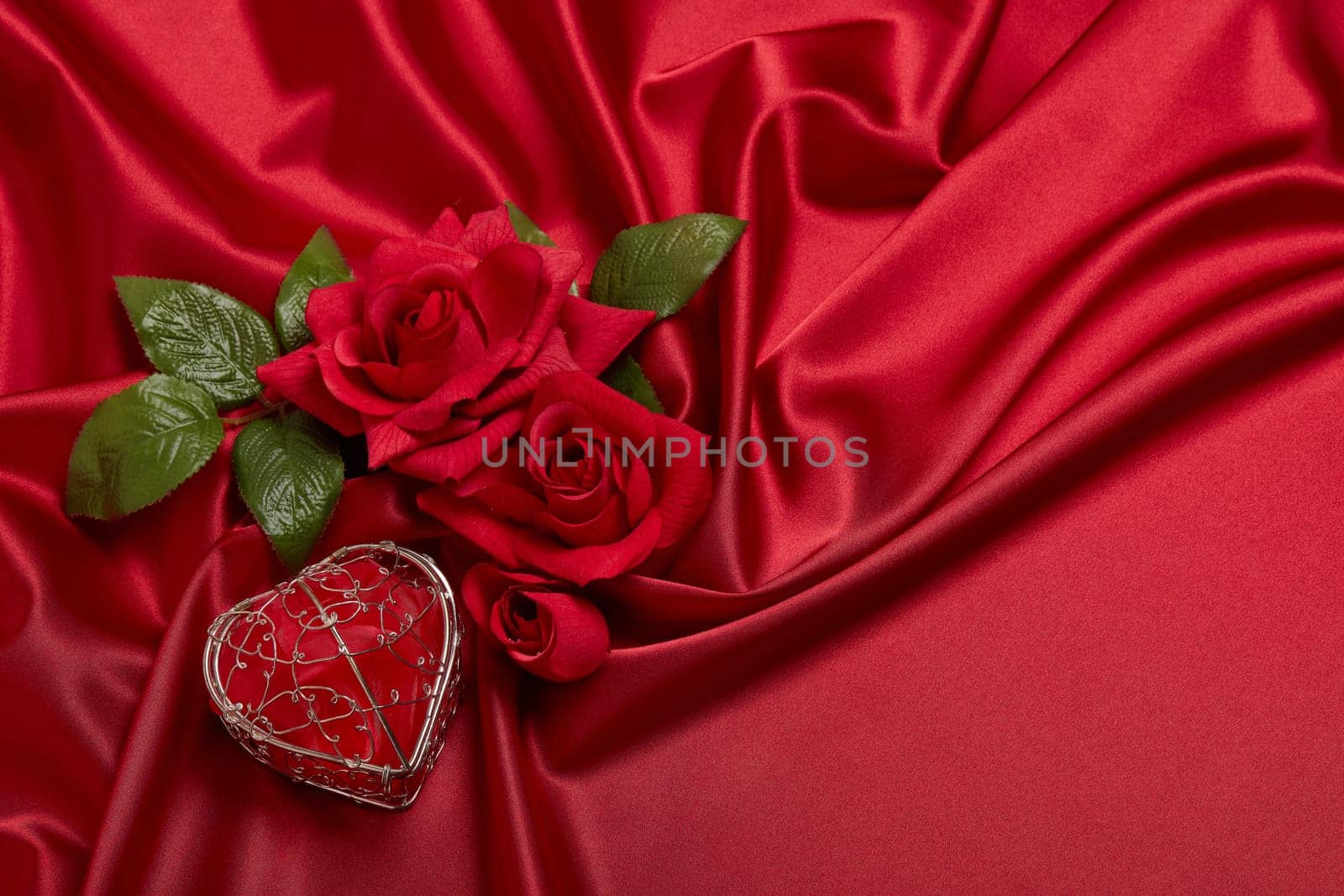 Abstract background from red silk (satin), roses and heart. Fabric texture with draped. Top view with copy space. Element design. Valentine's day. Wedding day.  Women' s day. Greeting card