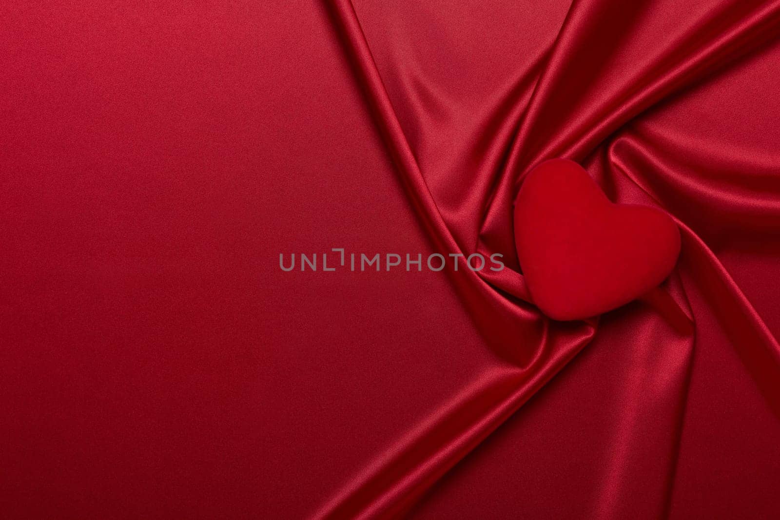 Abstract background from red silk (satin) and heart. Fabric texture with draped. Top view with copy space. Element design. Valentine's day. Wedding day. Greeting card