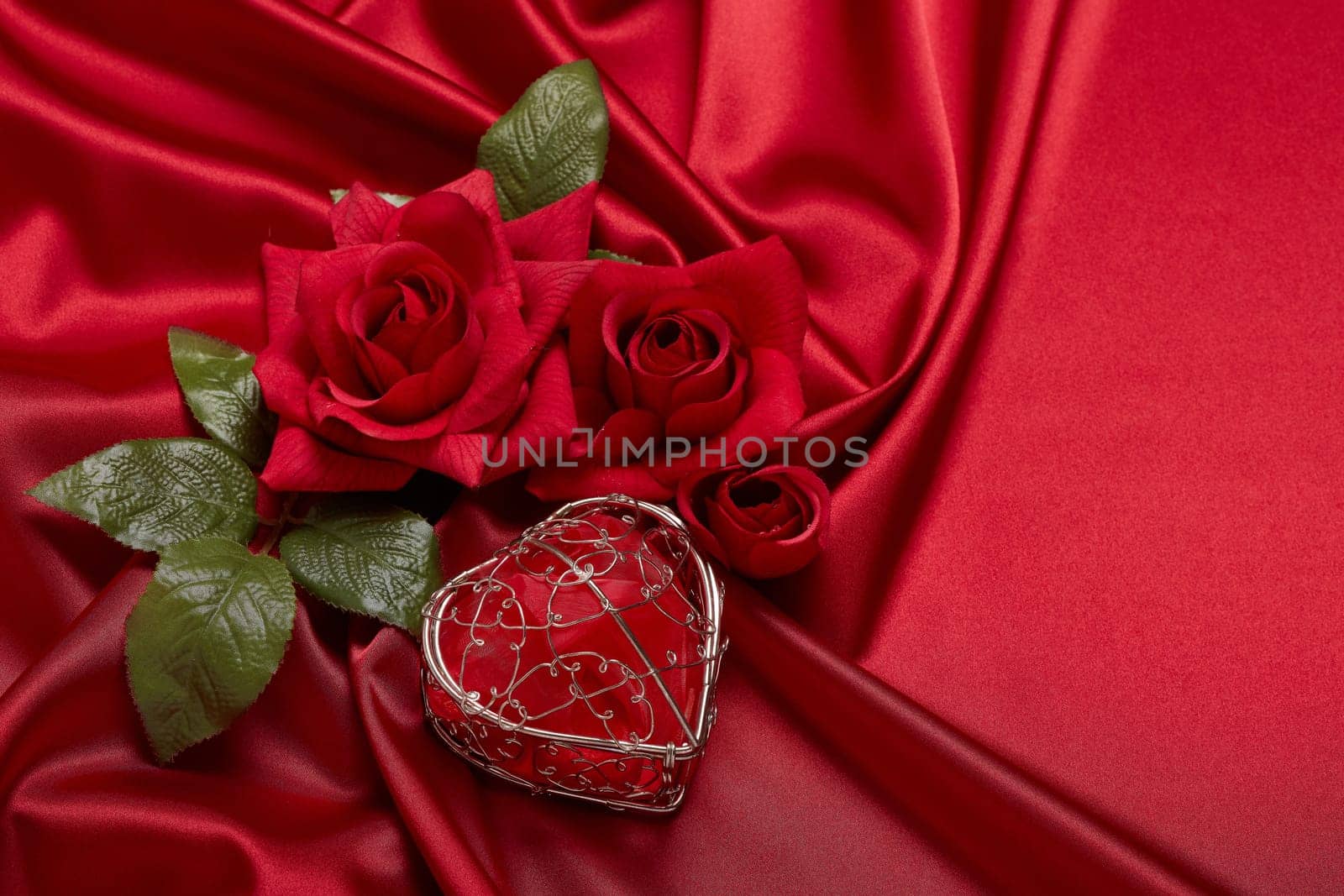 Abstract background from red silk (satin), roses and heart. Fabric texture with draped. Top view with copy space. Element design. Valentine's day. Wedding day.  Women' s day. Greeting card
