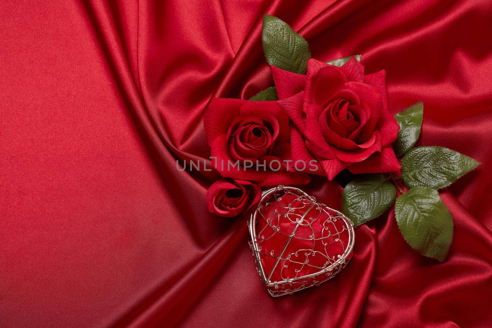 Abstract background from red silk (satin), roses and heart. Fabric texture with draped. Top view with copy space. Element design. Valentine's day. Wedding day.  Women' s day. Greeting card