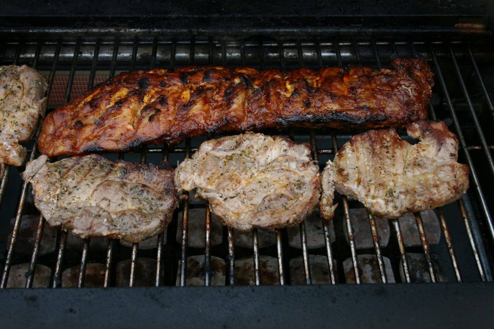 A large piece of meat and four small on a gas Grill