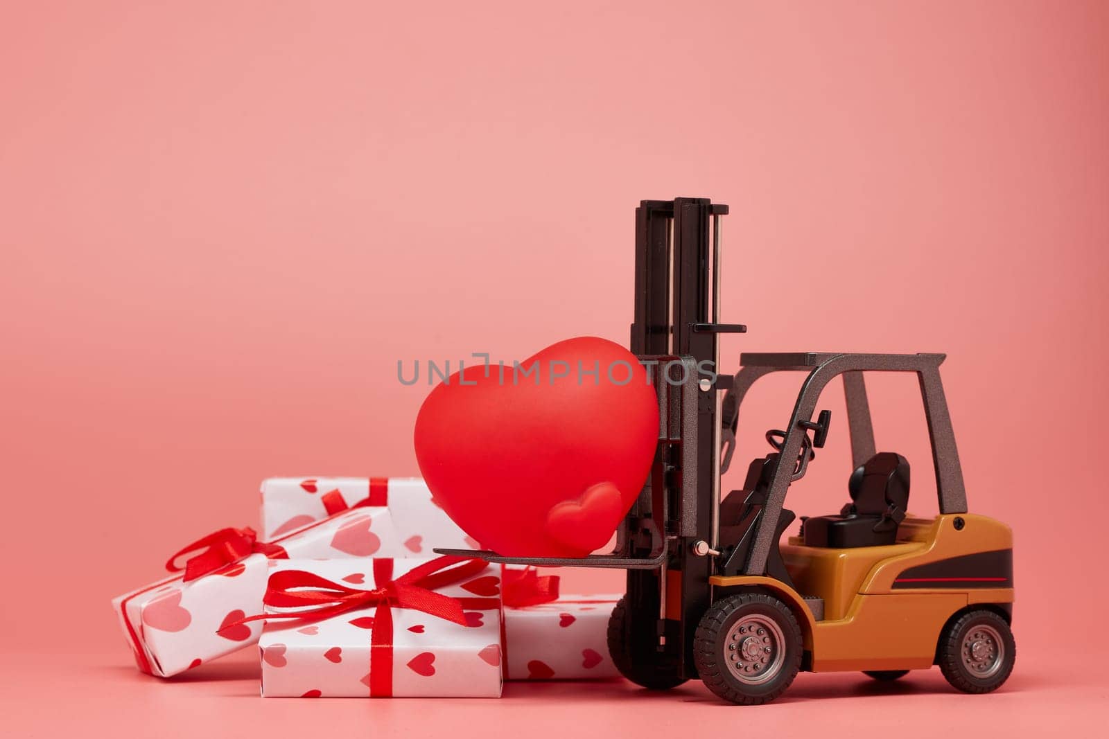 Forklift, red heart and gift boxes on pink background. Valentine's Day. Wedding Day