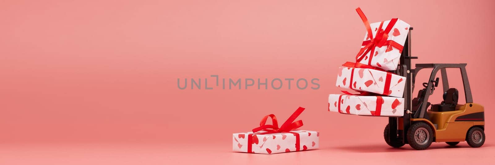 Forklift and gift boxes on pink background with copy space. Valentine's Day. Wedding Day