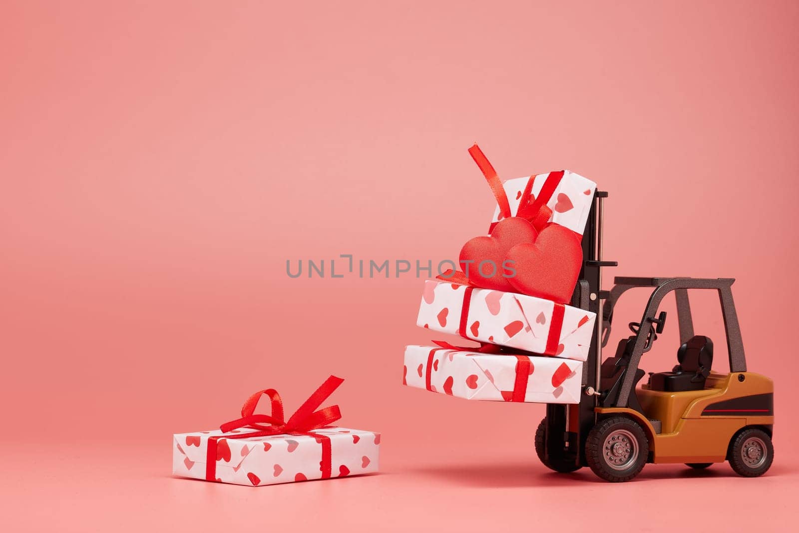 Forklift and gift boxes on pink background with copy space. Valentine's Day. Wedding Day