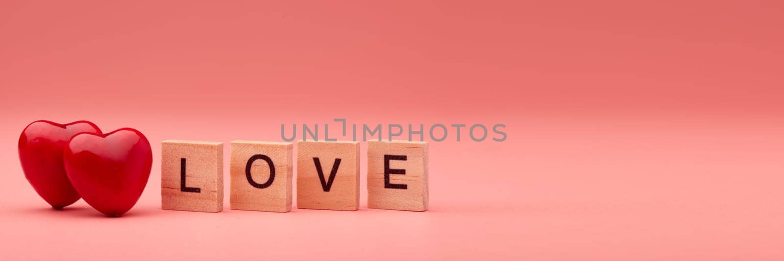 Two decorative hearts and inscription love from wooden letters on pink background with copy space. Valentine's Day. Wedding Day. Design element for romantic greeting card,  invitation.