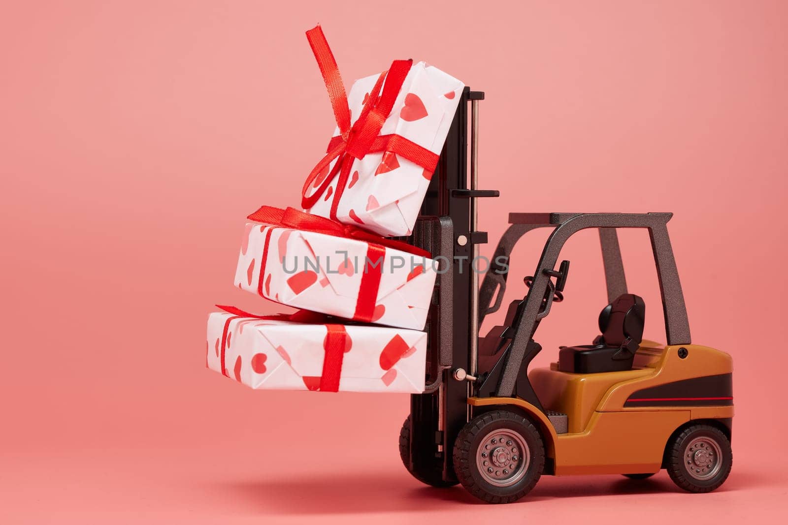 Forklift and gift boxes on pink background with copy space. Valentine's Day. Wedding Day