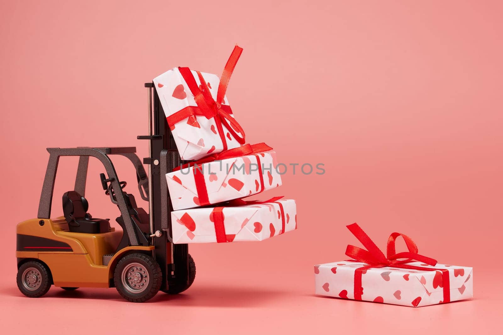 Forklift and gift boxes on pink background with copy space. Valentine's Day. Wedding Day