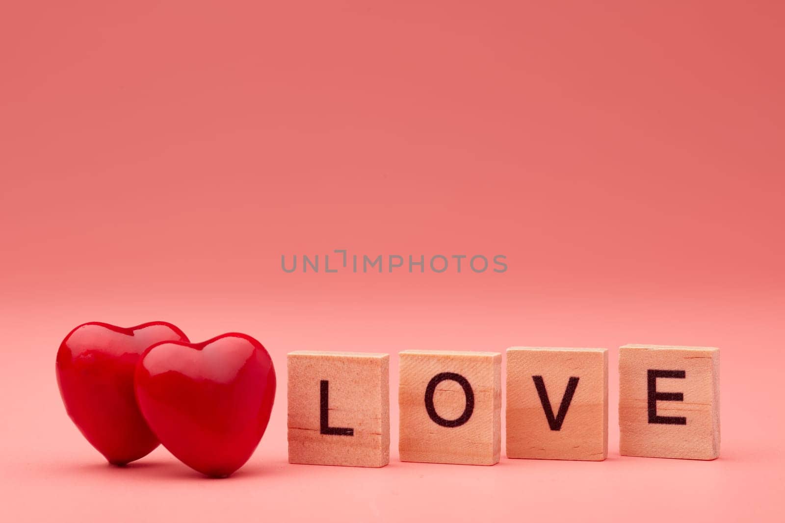 Two decorative hearts and inscription love from wooden letters on pink background with copy space. Valentine's Day. Wedding Day. Design element for romantic greeting card,  invitation.