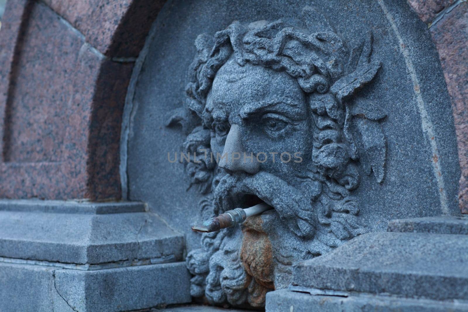 medieval street drinking fountain with stone human head