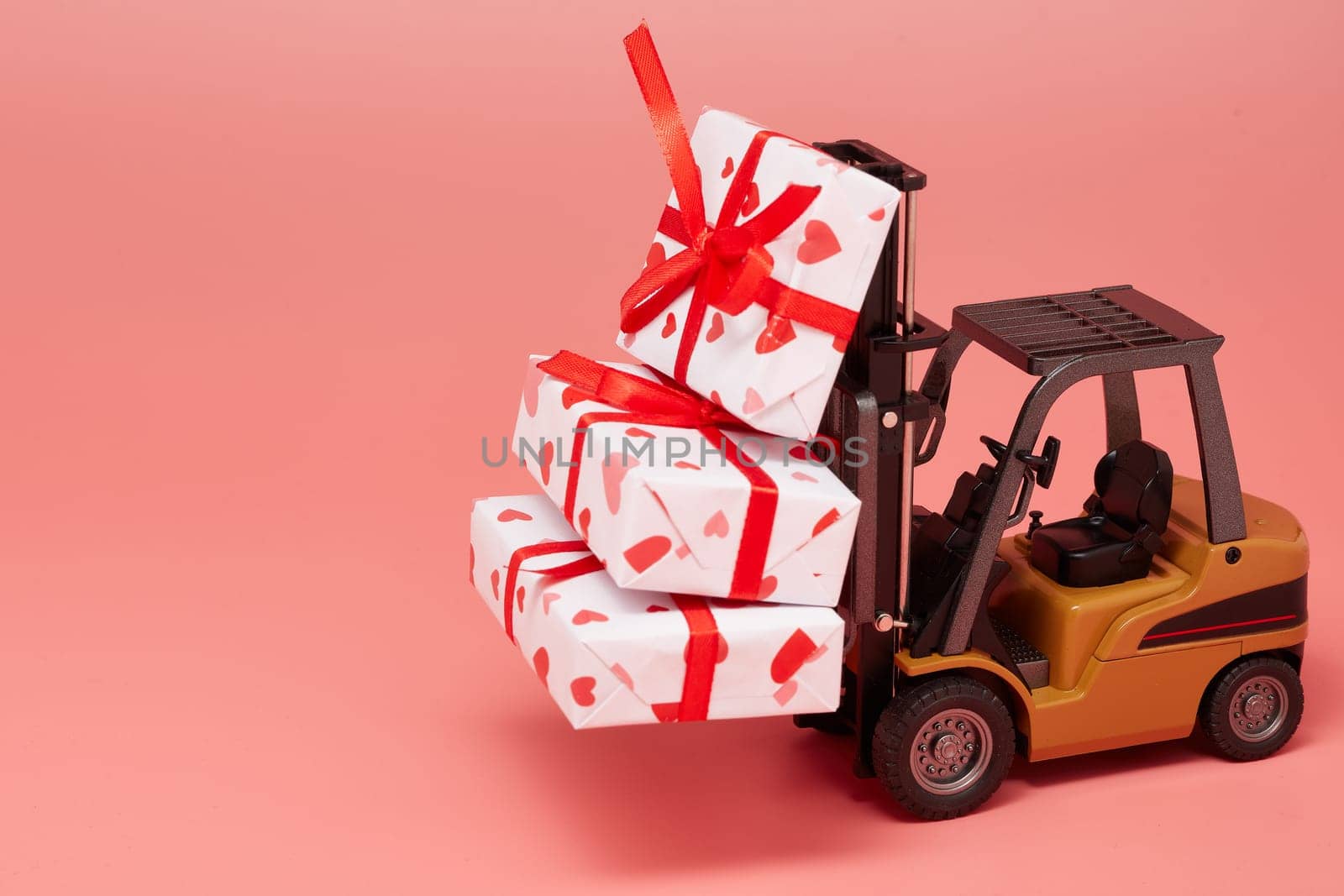 Forklift and gift boxes on pink background with copy space. Valentine's Day. Wedding Day