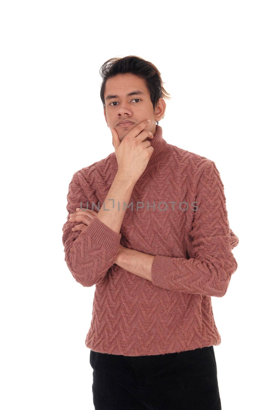 A tall young man standing in a burgundy sweater with one hand on .his chin thinking hard, isolated for white background.