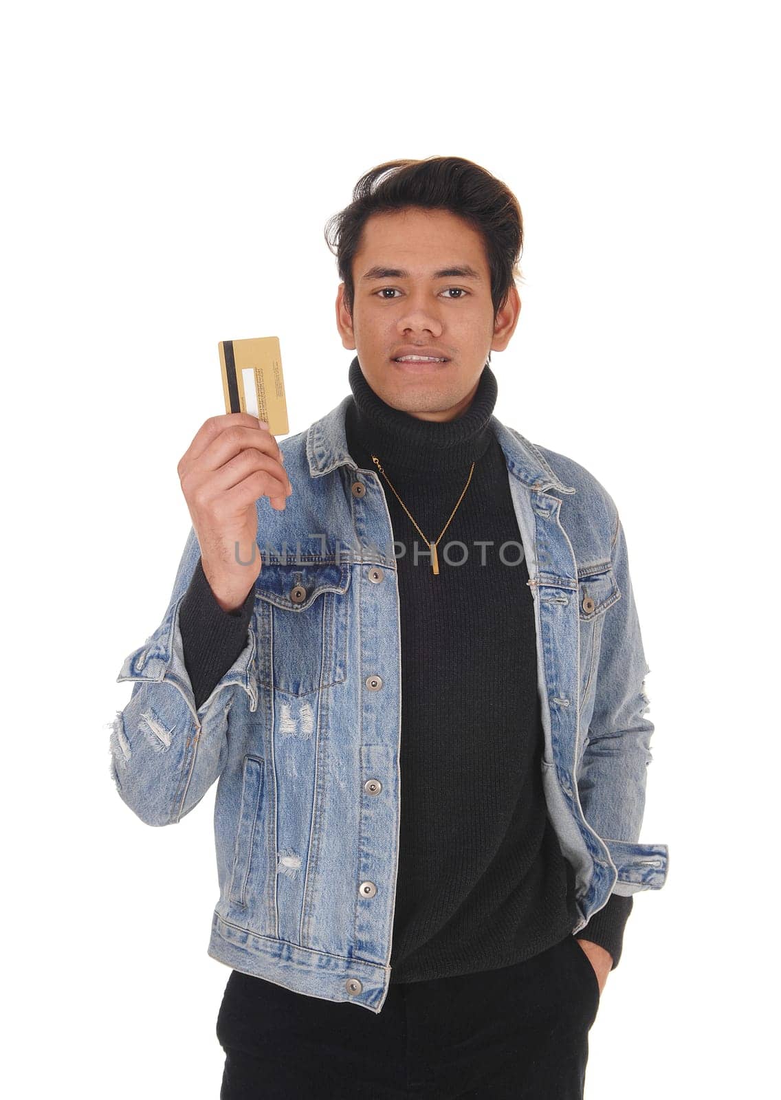 A happy young man in a jeans jacket smiling and showing his new.credit card, isolated for white background.