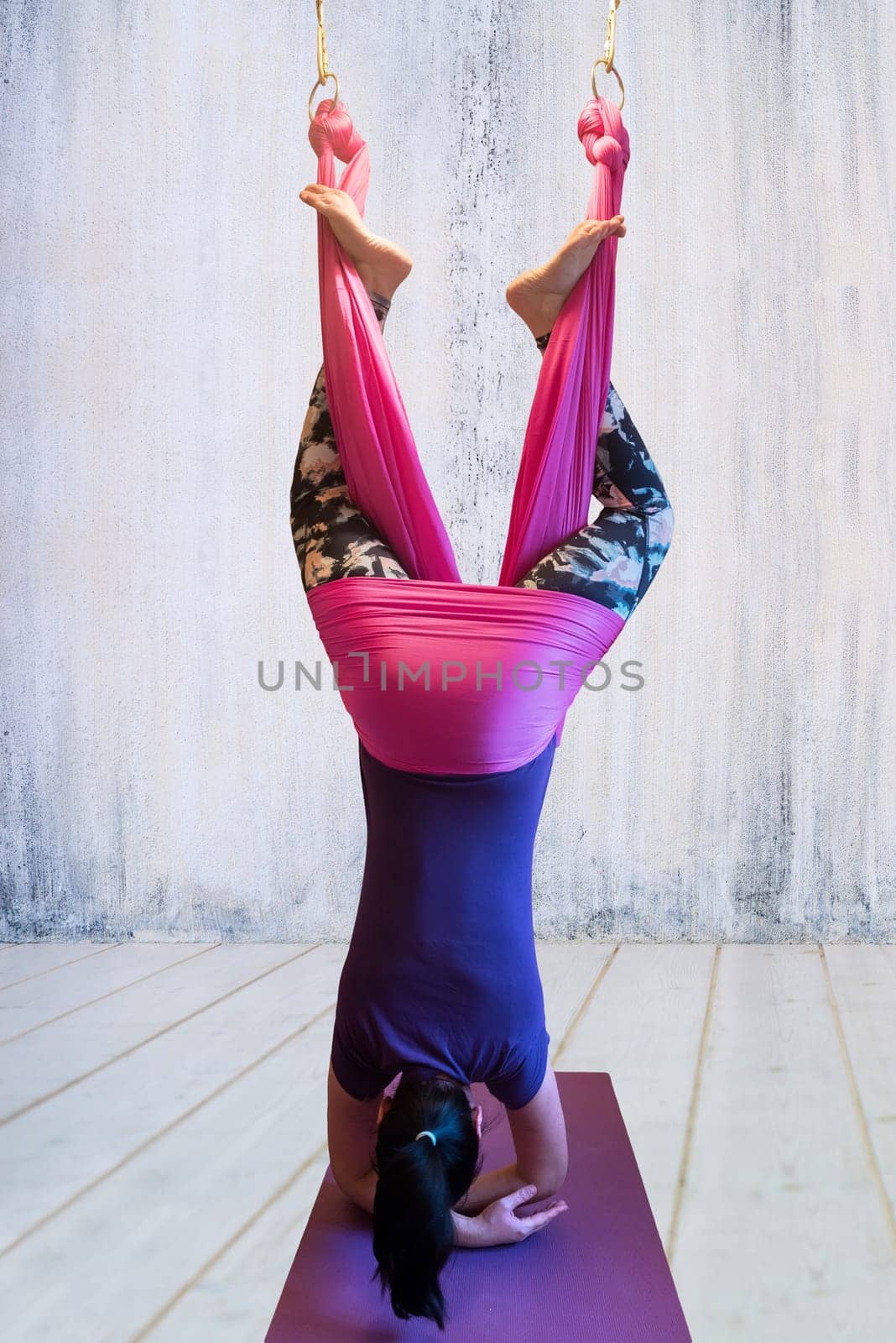 Young woman making antigravity yoga exercises in hammock