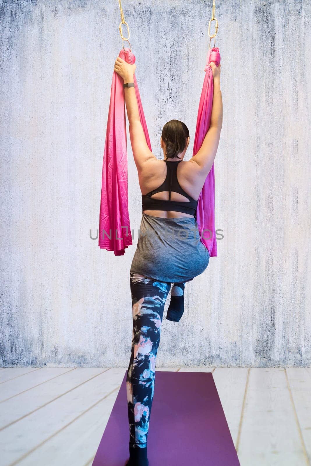 Young woman making antigravity yoga exercises in hammock