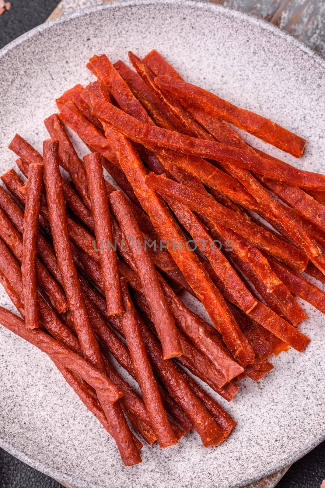 Jerky dried fish sticks with salt and spices on a dark concrete background