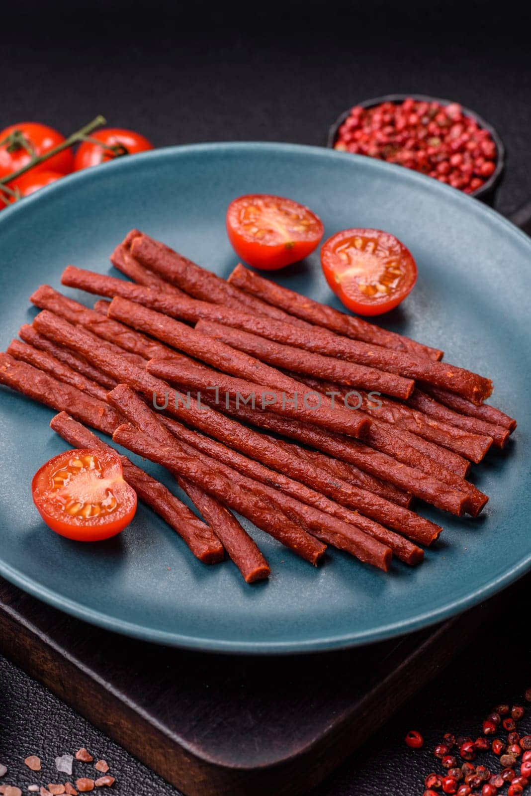 Jerky dried fish sticks with salt and spices on a dark concrete background