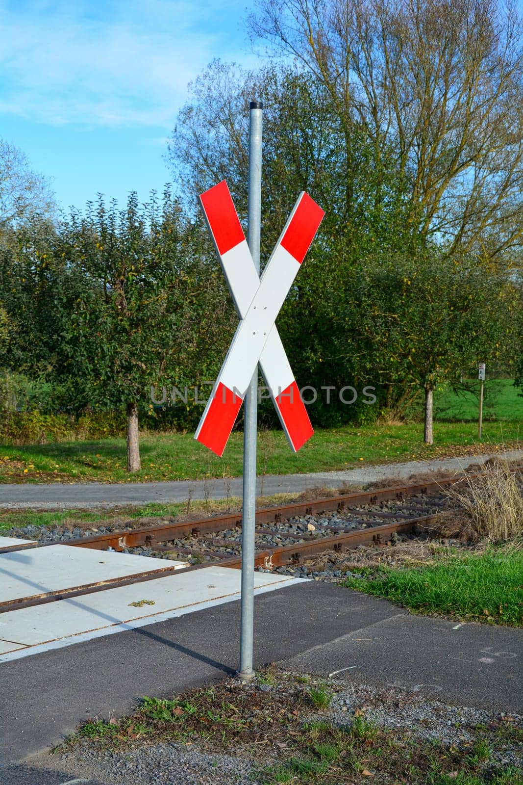 Unattended level crossing with St. Andrew's cross in sunlight with blue sky