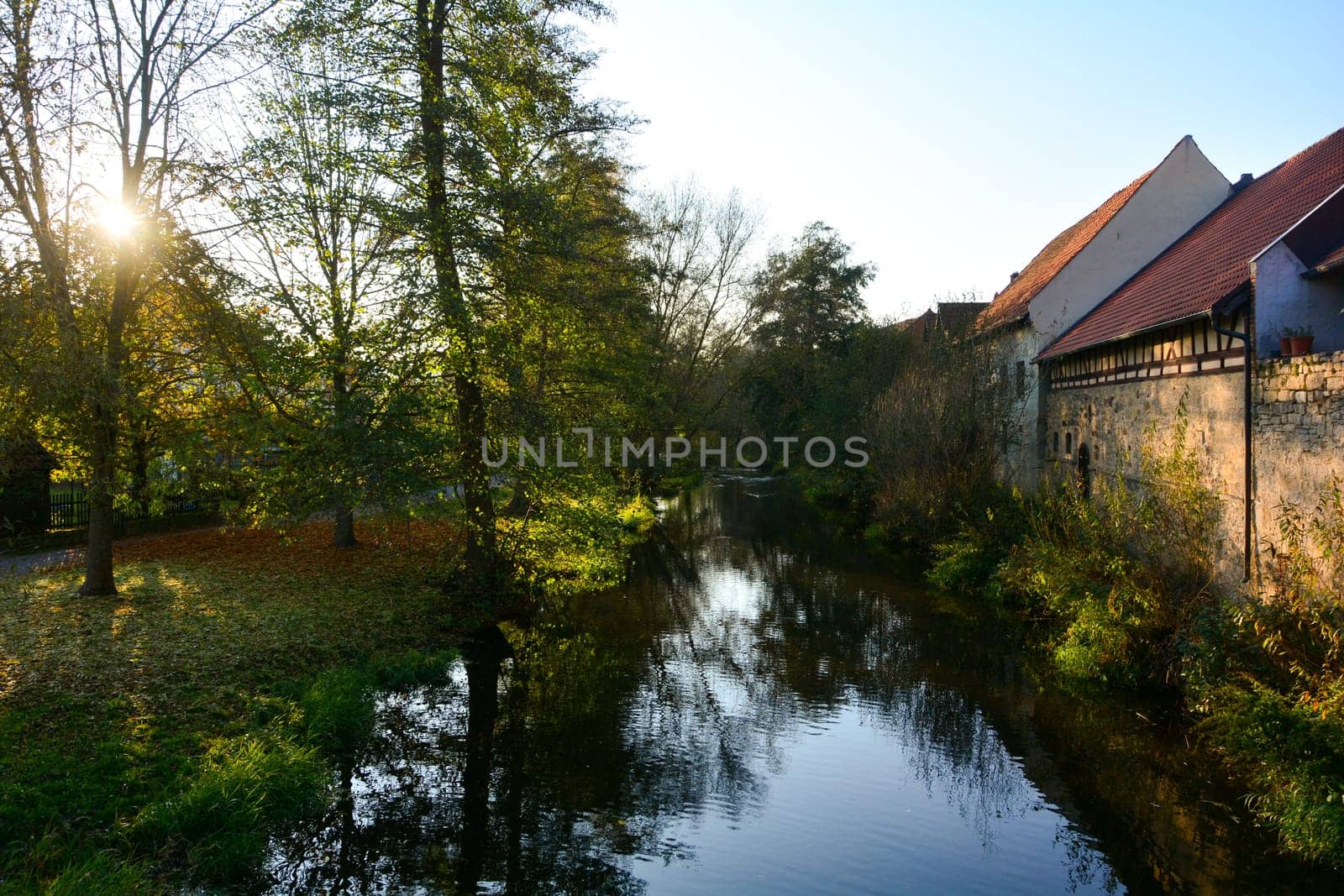 Creek with nature and old houses in the evening light,with sun n Ostheim , Rhoen, Bavaria, Germany