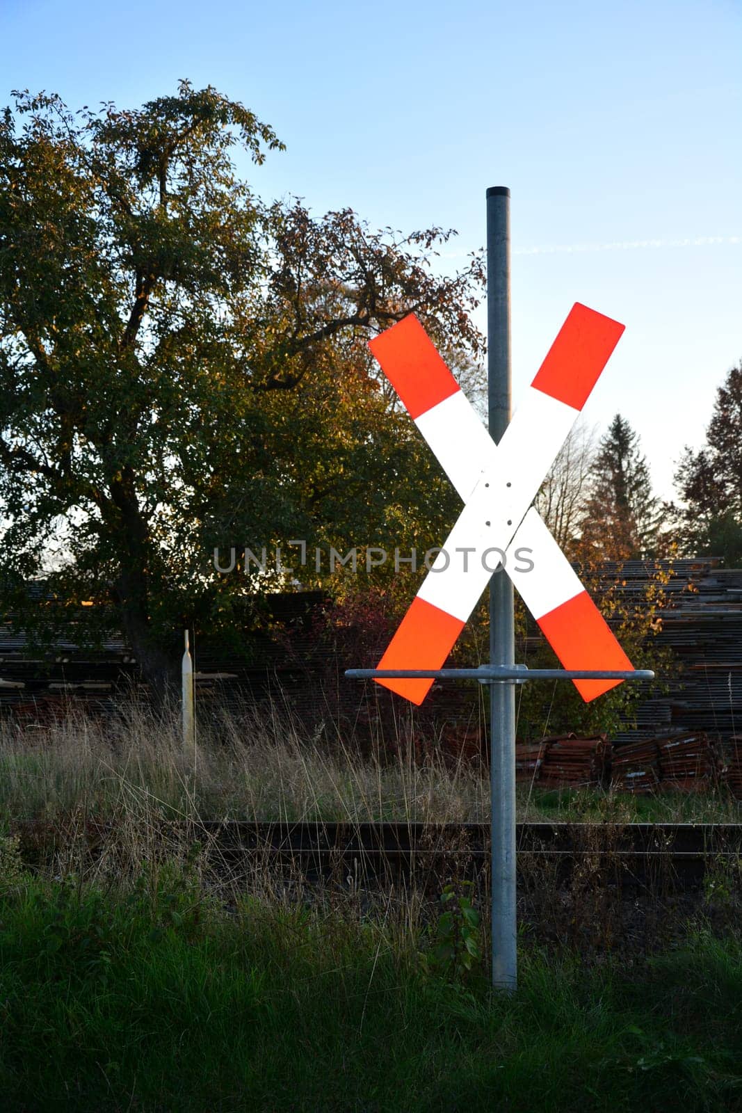 St. Andrew's cross before rails with tree, grass and woods