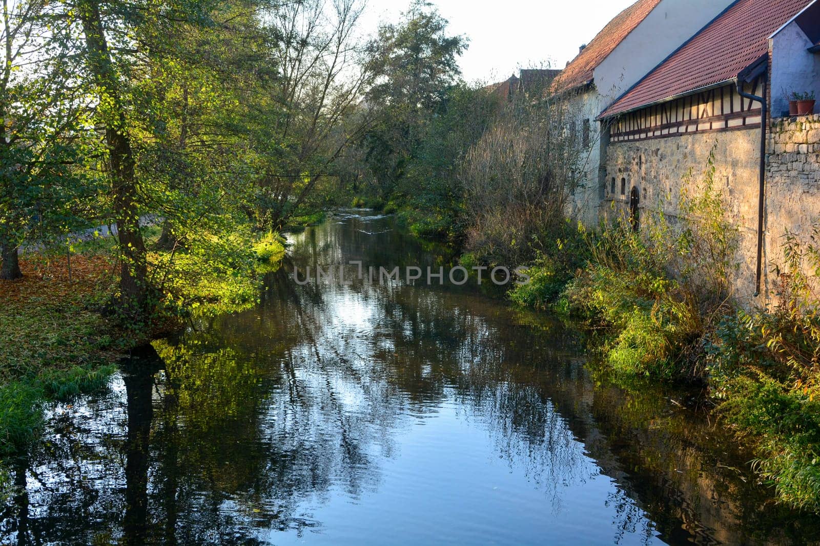 Creek with nature and old houses in the evening light,with reflection  n Ostheim , Rhoen, Bavaria, Germany